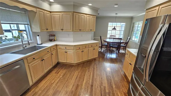 a kitchen with stainless steel appliances granite countertop a refrigerator a sink dishwasher a stove and white countertops with wooden floor