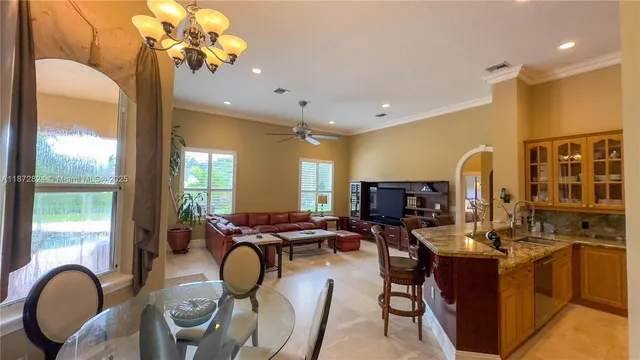 a dining room filled chandelier and kitchen view