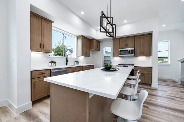 a large kitchen with stainless steel appliances kitchen island granite countertop a sink dishwasher a stove and a refrigerator with wooden floor