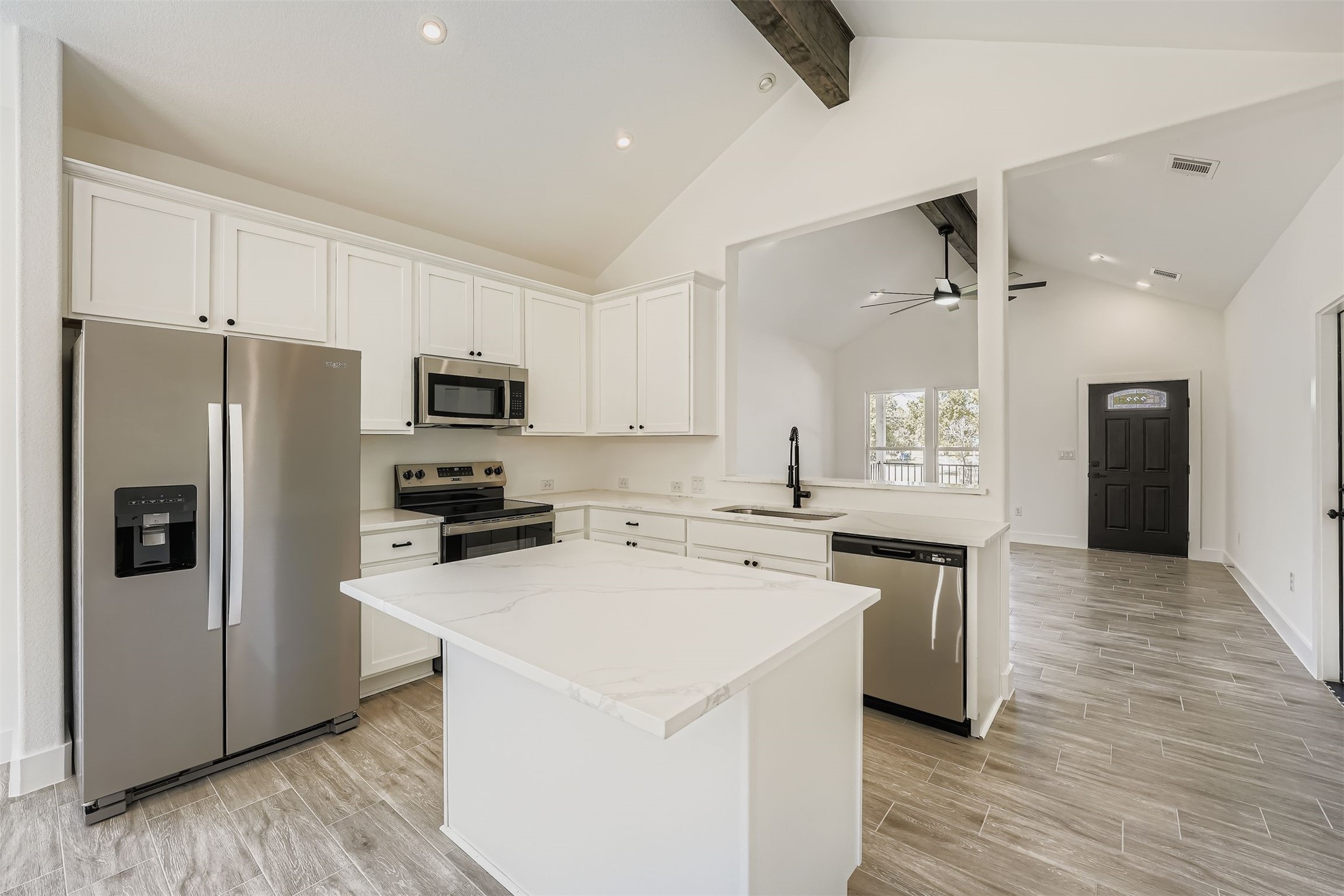 701 East 3rd Street Elgin, TX 78621 - Photo 7 of 35 Kitchen with stainless steel appliances, white cabinetry, a kitchen island, and beamed ceiling