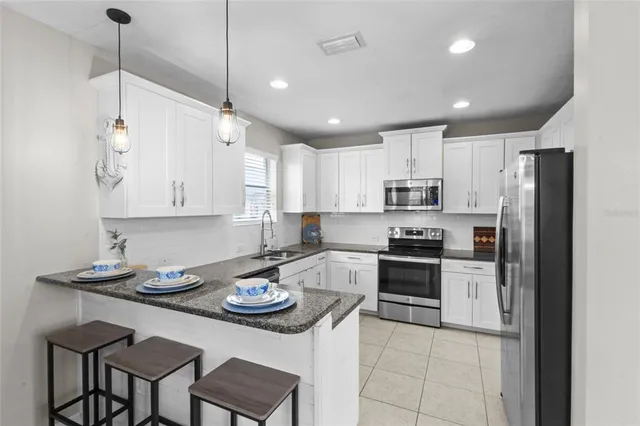 a kitchen with stainless steel appliances granite countertop a sink a stove a refrigerator cabinets and chairs