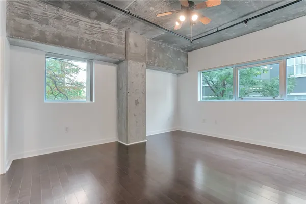 an empty room with wooden floor and windows