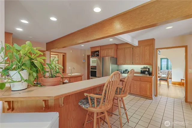 a kitchen with stainless steel appliances kitchen island granite countertop a table and chairs in it