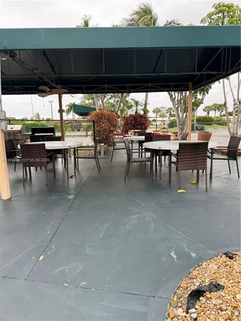 a view of a patio with table and chairs under an umbrella with a large tree