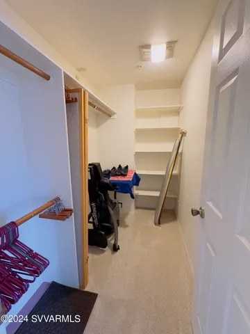 a view of walk in closet with clothes and shoes