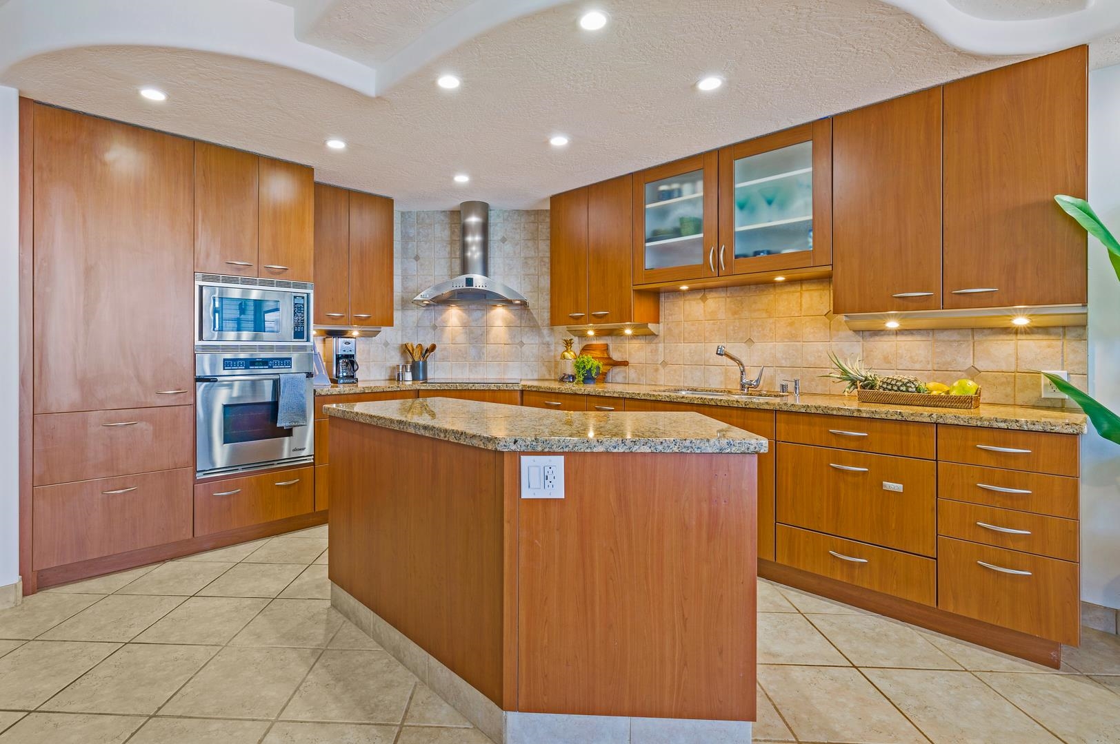 3875 Lower Honoapiilani Road, Unit B305 Lahaina, HI 96761 - Photo 27 of 35 a kitchen with kitchen island granite countertop wooden cabinets and a sink