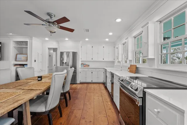 a large kitchen with stainless steel appliances granite countertop a stove top oven a sink a dining table and chairs