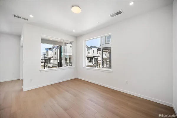 an empty room with wooden floor and windows