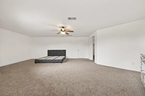 a view of an empty room with a chandelier fan