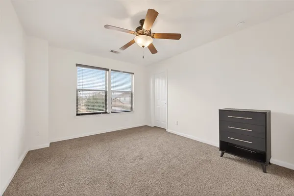 a view of an empty room with a window and a ceiling fan