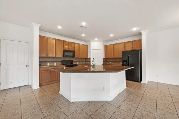 a large kitchen with stainless steel appliances granite countertop a refrigerator a stove a sink and a microwave