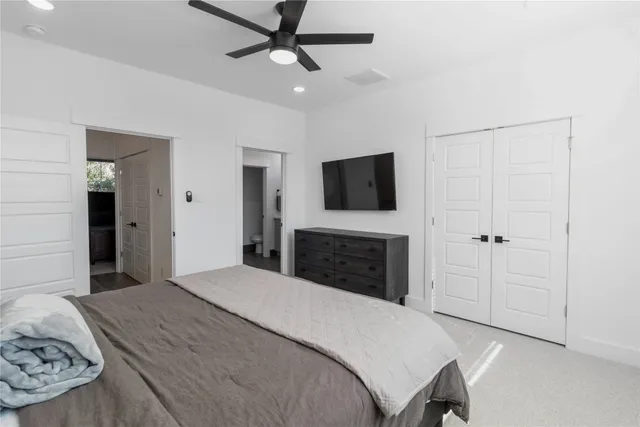 a bedroom with a large bed a flat tv screen and a dresser