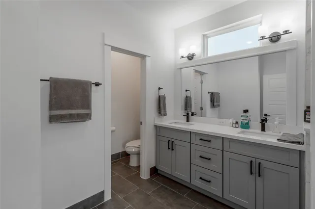 a spacious bathroom with a double vanity sink a mirror and a toilet