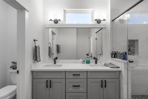 a bathroom with a double vanity sink mirror and toilet