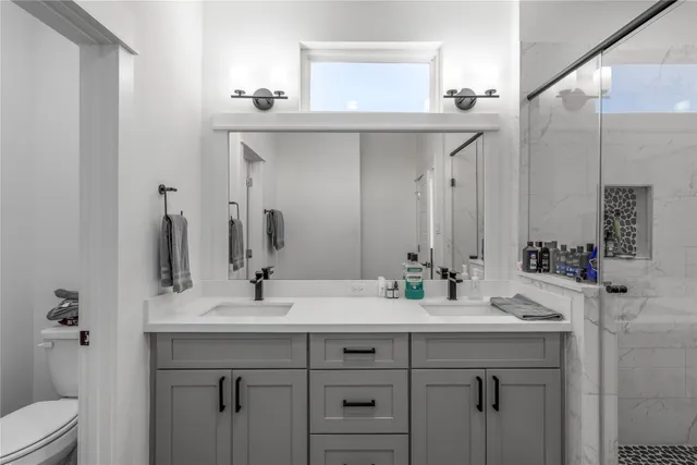 a bathroom with a double vanity sink mirror and toilet