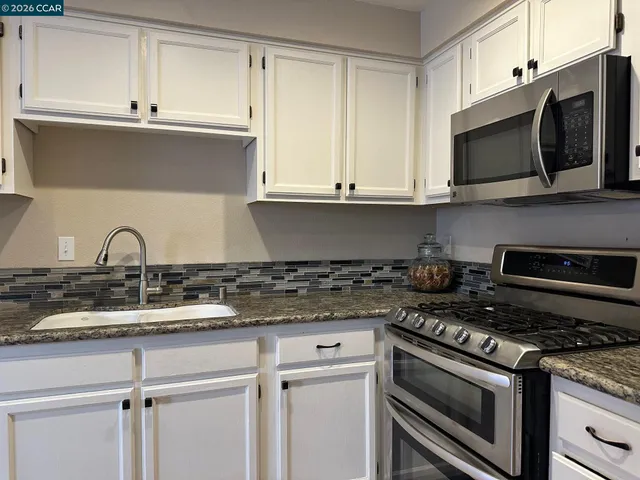 a kitchen with stainless steel appliances granite countertop a sink and a stove