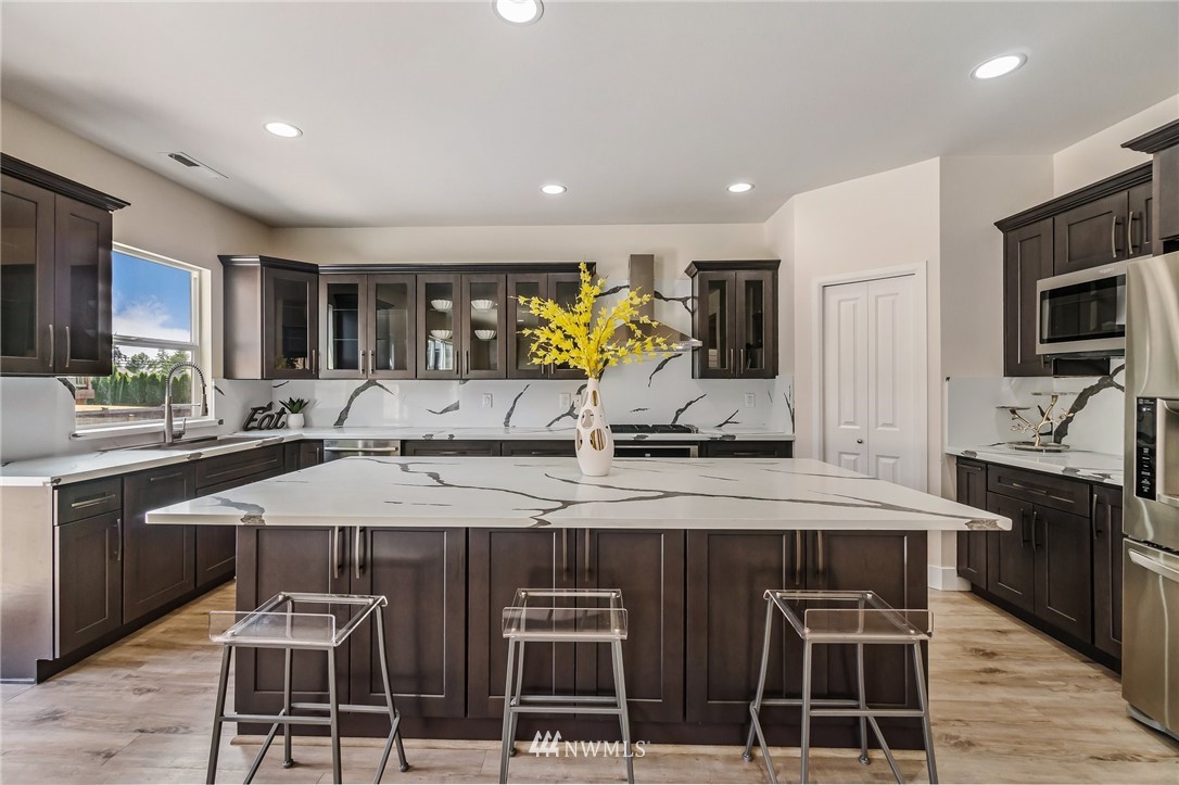 4122 167th Place Southeast Bothell, WA 98012 - Photo 12 of 40 a kitchen with stainless steel appliances granite countertop a stove a sink a oven a dining table and chairs