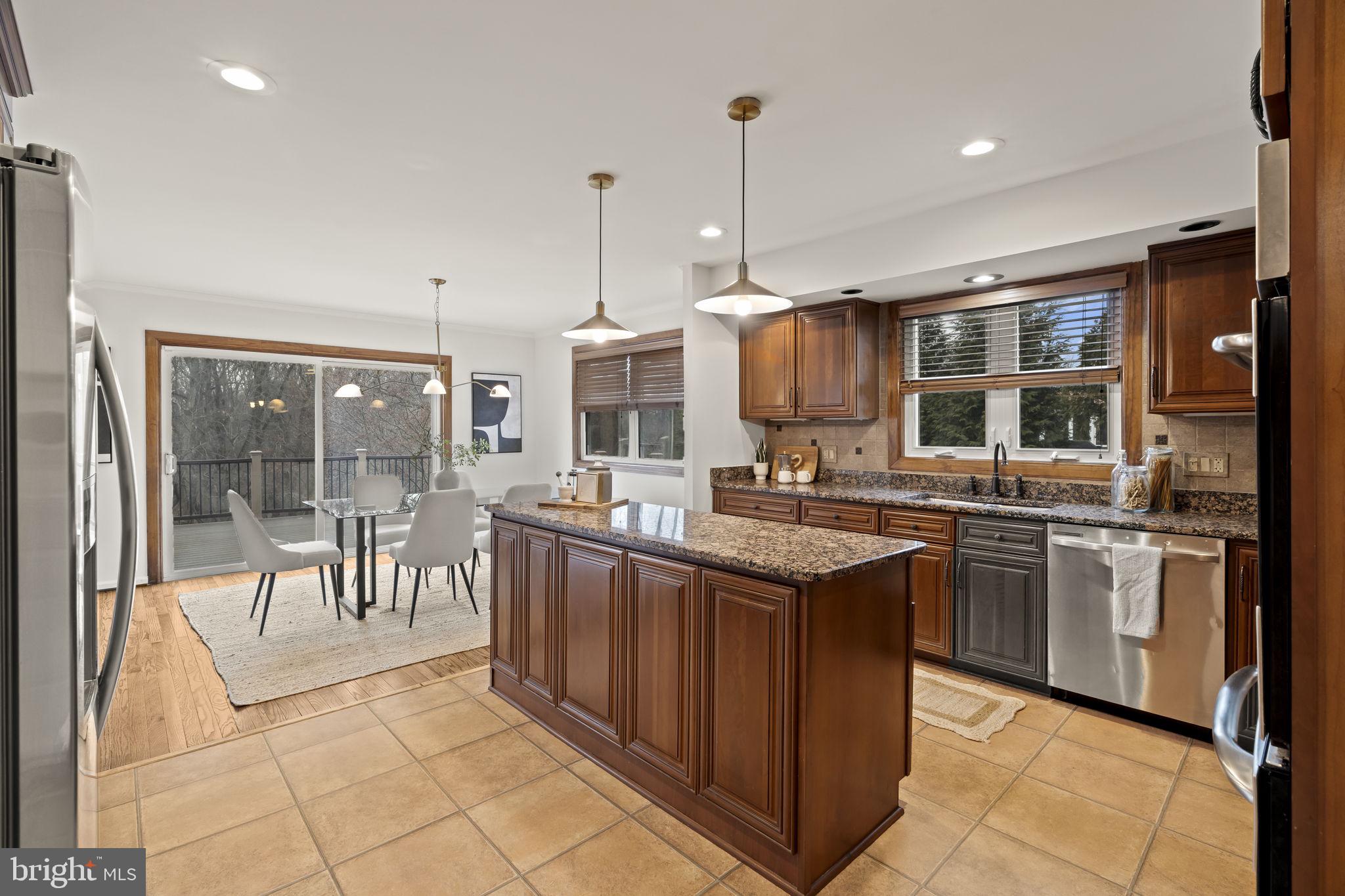 49 Langstoon Lane Media, PA 19063 - Photo 17 of 64 a kitchen with stainless steel appliances granite countertop a stove top oven a sink dishwasher a dining table and chairs with wooden floor