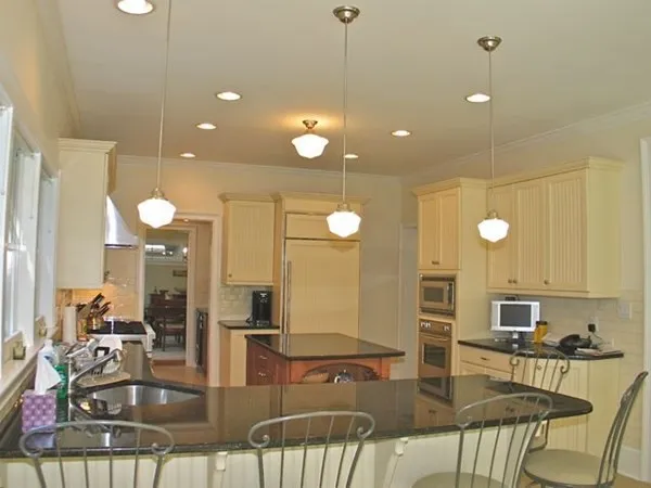 an open kitchen with granite countertop a stove and white cabinets