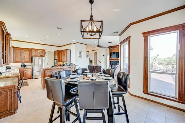 a kitchen with stainless steel appliances granite countertop a stove a refrigerator a kitchen island dining table and chairs