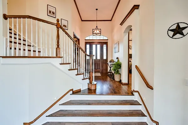 a view of staircase with lots of frames on wall and wooden floor