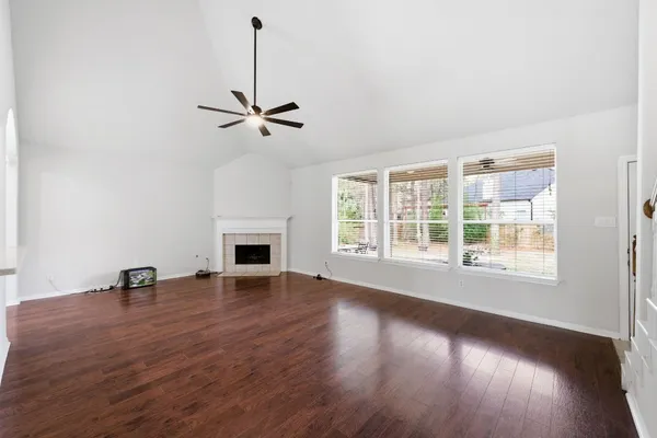 an empty room with wooden floor fireplace and windows