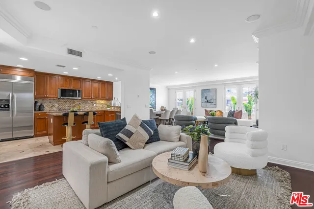 a living room with furniture kitchen view and a wooden floor