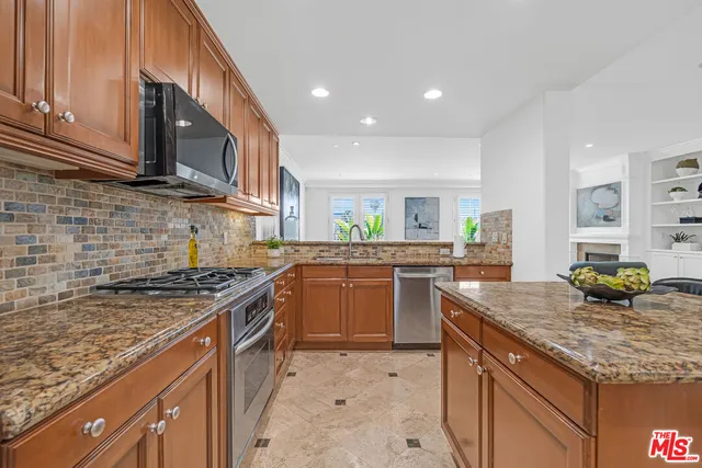 a kitchen with stainless steel appliances granite countertop a stove a sink and a microwave