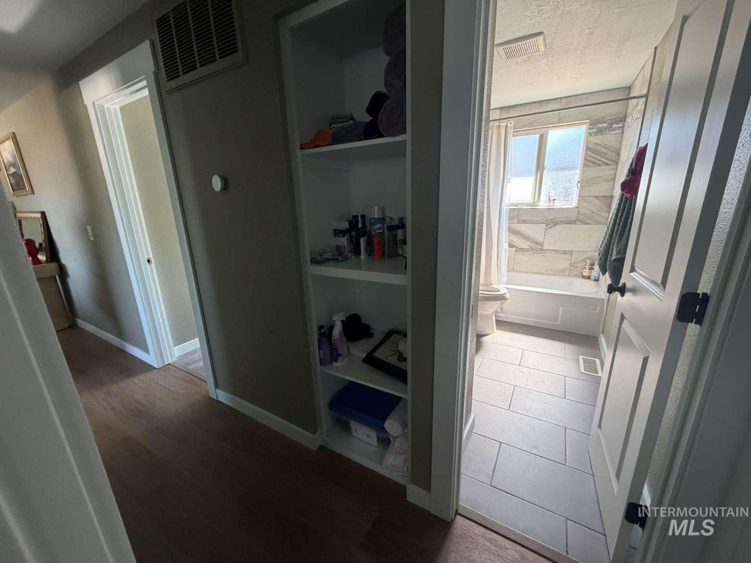 9951 West Fox Ridge Drive Boise, ID 83709 - Photo 8 of 13 Bathroom entrance featuring a built-in shelving unit, wood-finish flooring, and a white paneled door