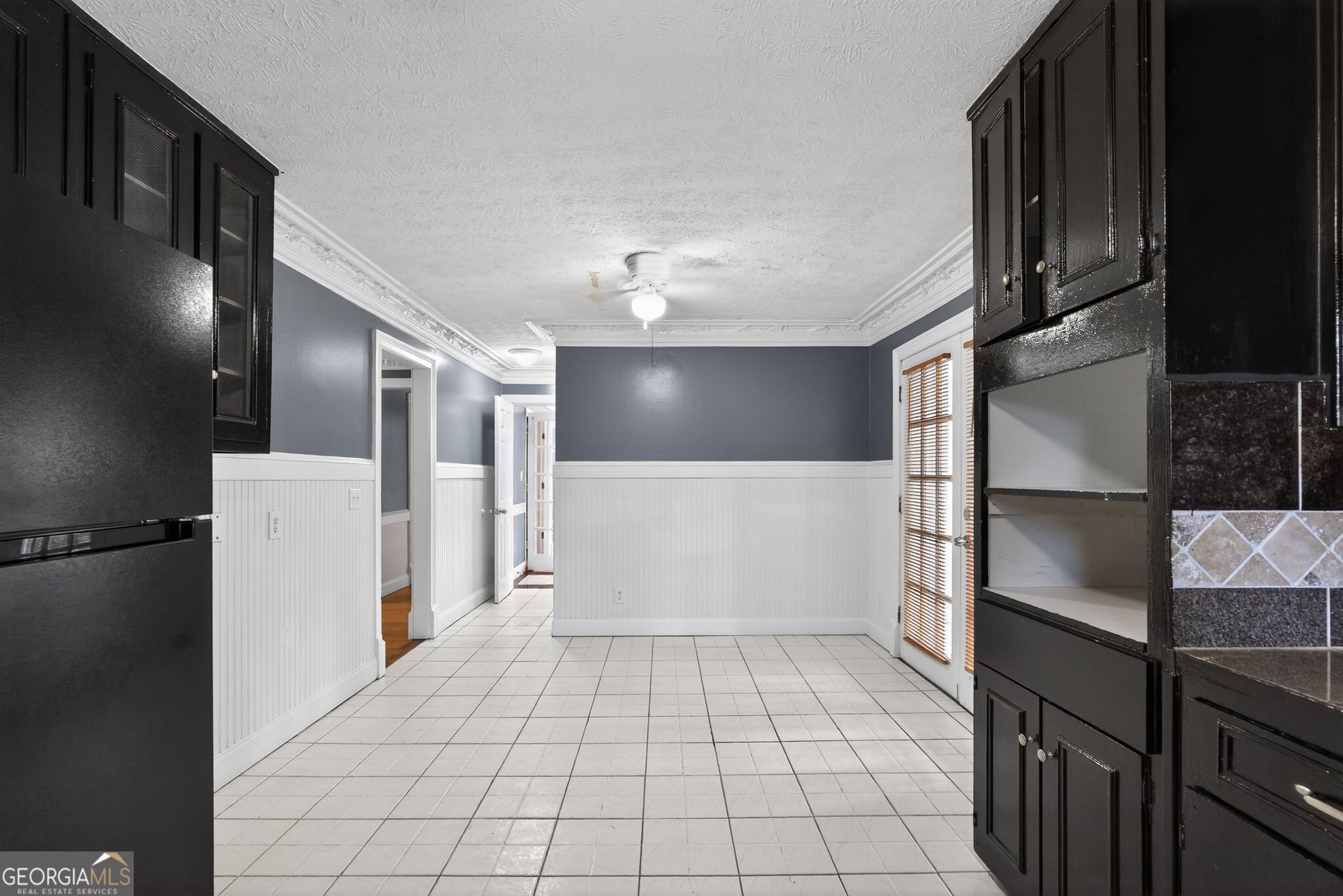6581 Woodrow Road Lithonia, GA 30038 - Photo 12 of 34 a view of a refrigerator in kitchen and an empty room with wooden floor