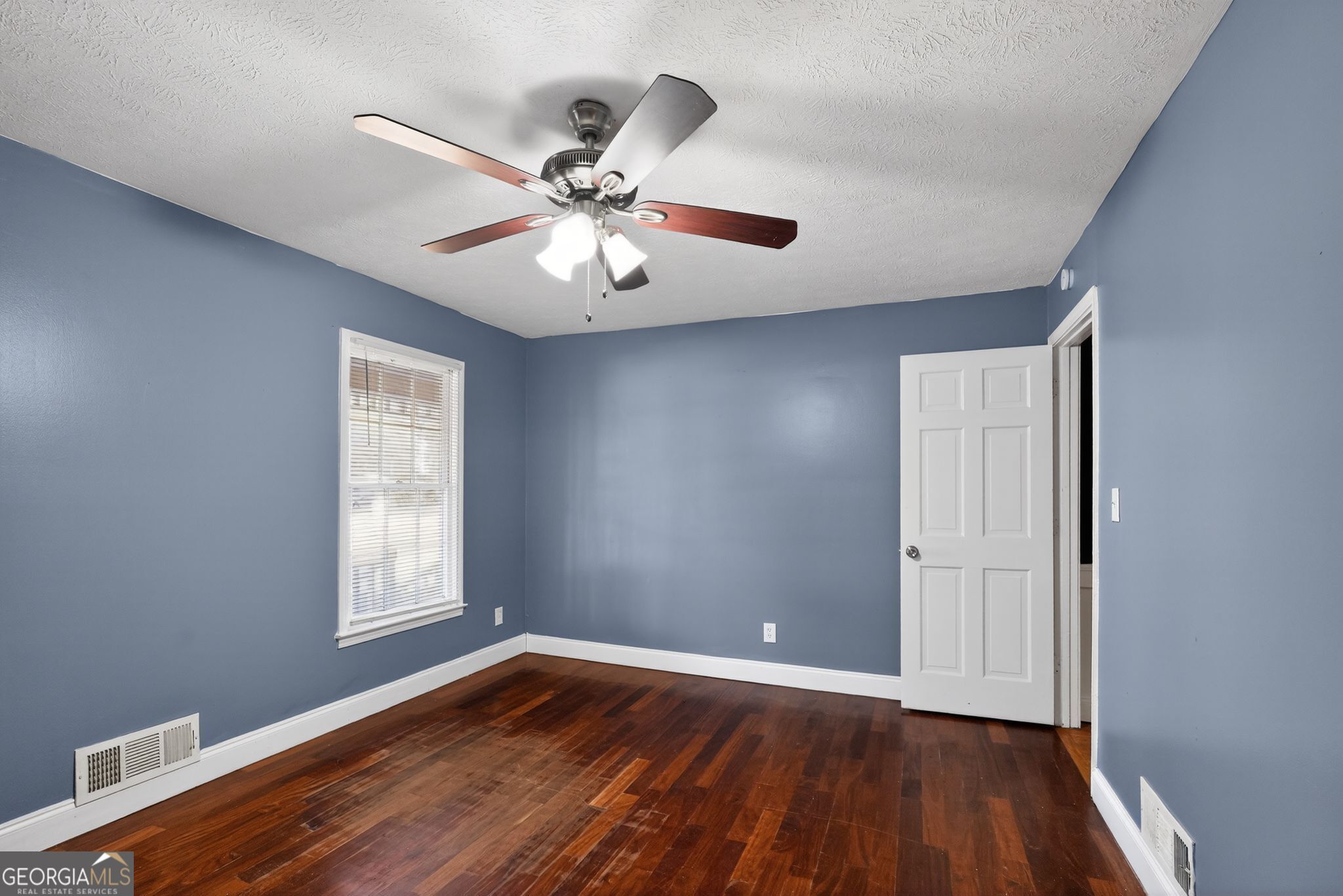 6581 Woodrow Road Lithonia, GA 30038 - Photo 17 of 34 an empty room with wooden floor chandelier fan and windows