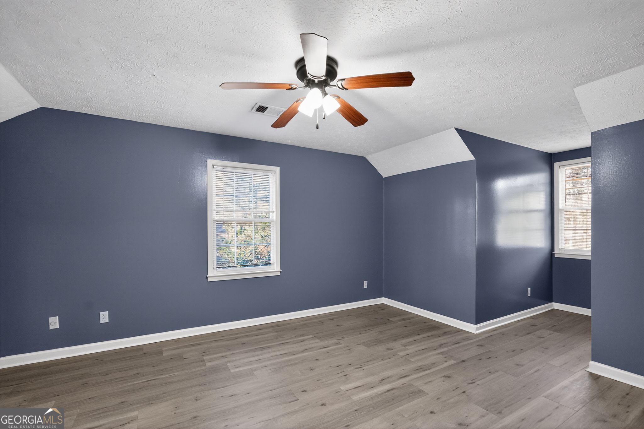 6581 Woodrow Road Lithonia, GA 30038 - Photo 27 of 34 an empty room with wooden floor chandelier fan and windows
