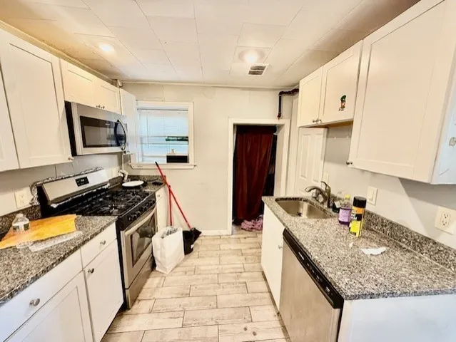 a kitchen with stainless steel appliances granite countertop a sink stove refrigerator and cabinets
