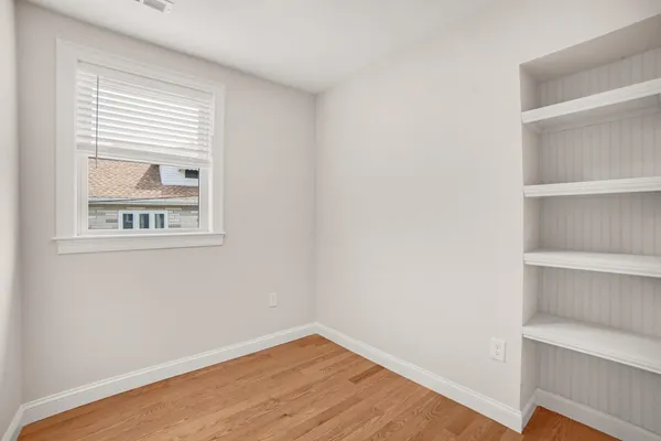 a view of an empty room with a window and wooden floor