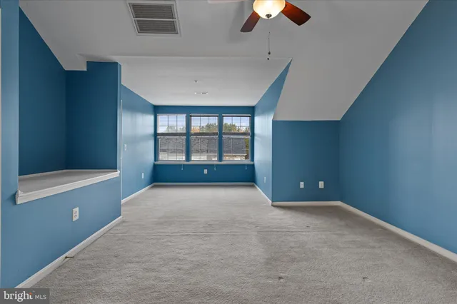 a view of an empty room with a window and a kitchen