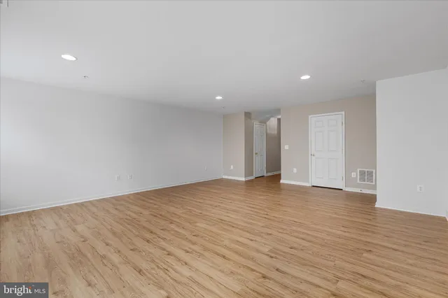 a view of an empty room with wooden floor and closet