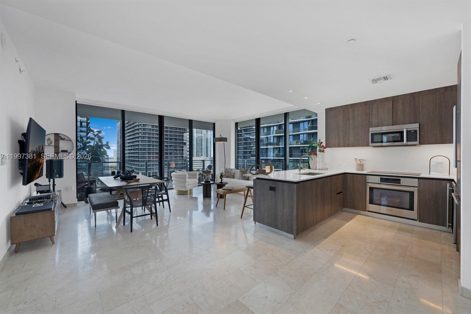 88 Southwest 7th Street, Unit 1401 Miami, FL 33130 - Photo 2 of 27 a kitchen with stainless steel appliances kitchen island granite countertop a stove a sink a dining table and chairs