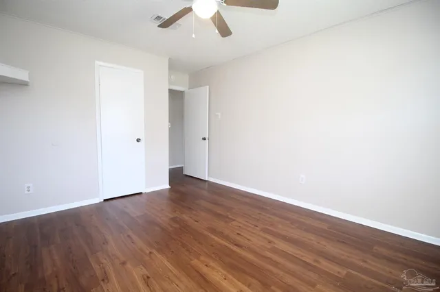an empty room with wooden floor and ceiling fan