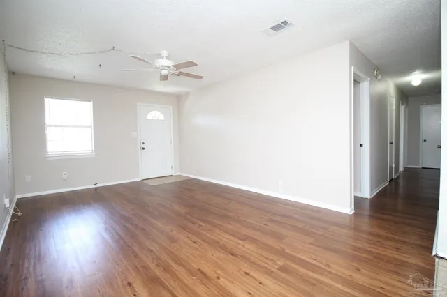 an empty room with wooden floor and windows