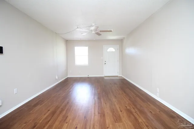an empty room with wooden floor and windows