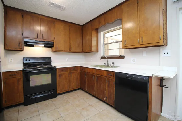 a kitchen with stainless steel appliances granite countertop wooden cabinets a stove top oven a sink and dishwasher