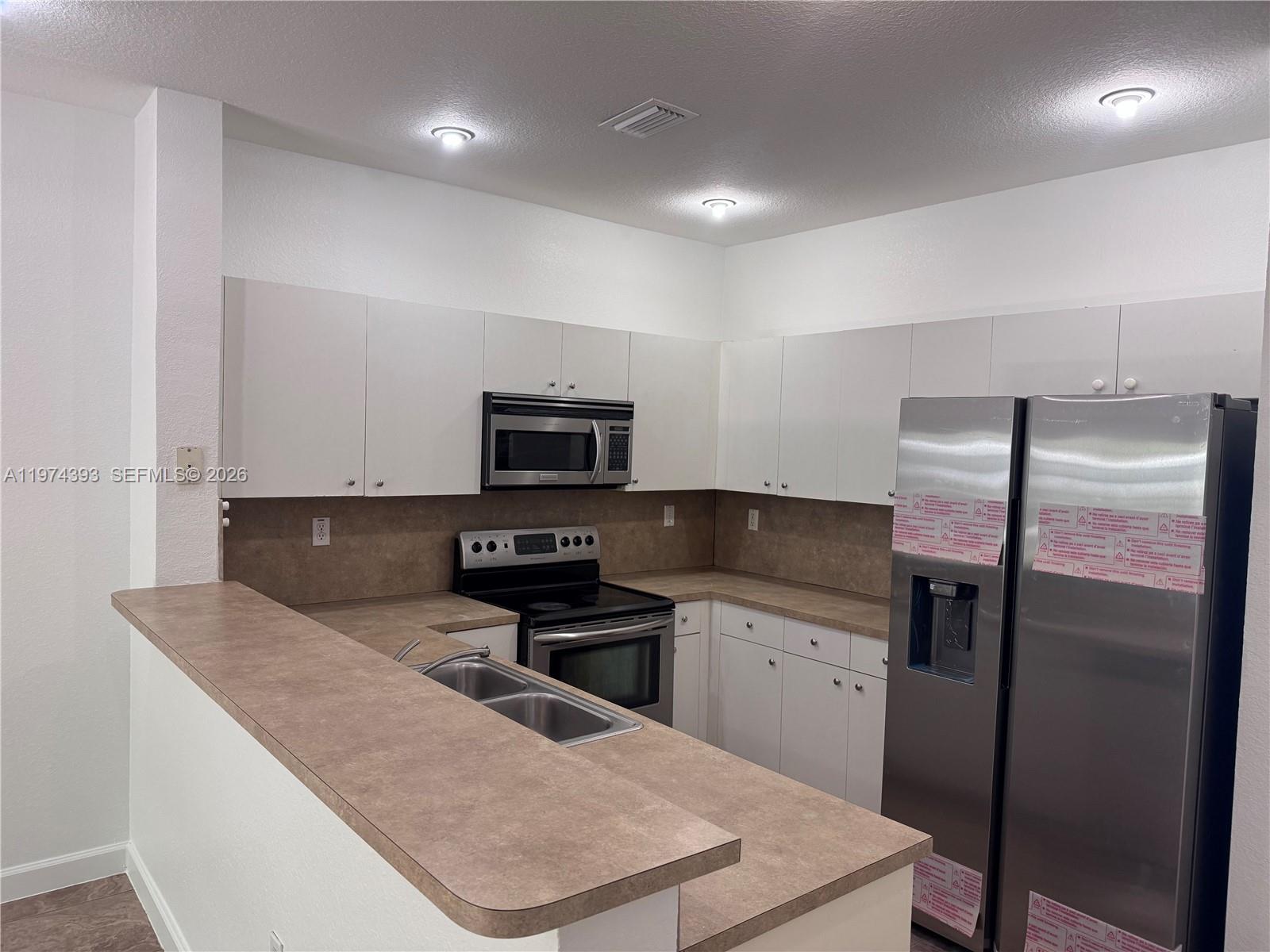 8500 Southwest 150th Avenue, Unit 3 Miami, FL 33193 - Photo 6 of 22 a kitchen with stainless steel appliances granite countertop a sink a microwave a refrigerator and white cabinets