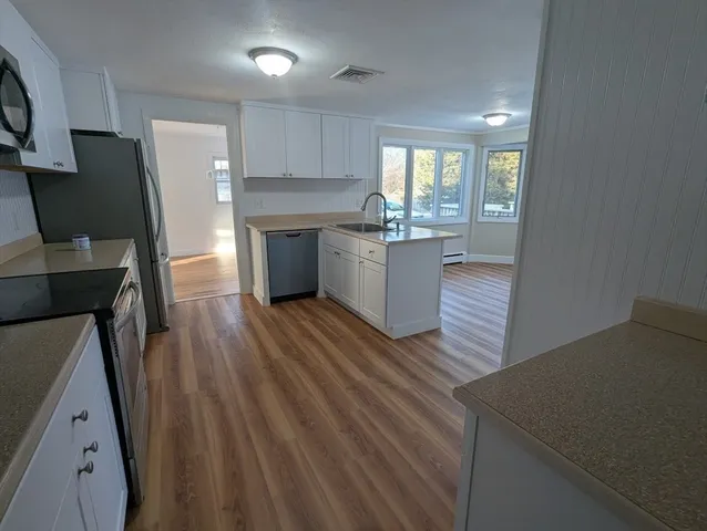 a kitchen with a wooden floor and a view of living room