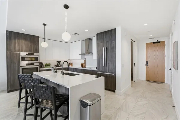 a kitchen with stainless steel appliances kitchen island granite countertop a table chairs and a refrigerator