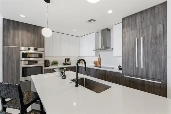 a kitchen with stainless steel appliances a sink dishwasher a refrigerator with white cabinets and wooden floor