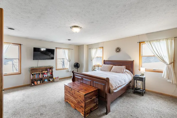 a bedroom with a bed and a flat tv screen on the dresser