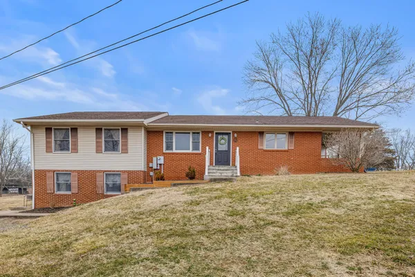 a front view of house with yard and trees in the background
