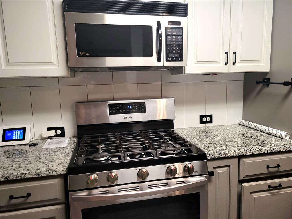 912 North Dove Road Grapevine, TX 76051 - Photo 9 of 36 a kitchen with granite countertop cabinets stove and microwave