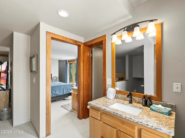 a en suite bathroom with a granite countertop sink and a mirror