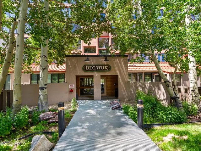 a front view of a house with a yard and tree s